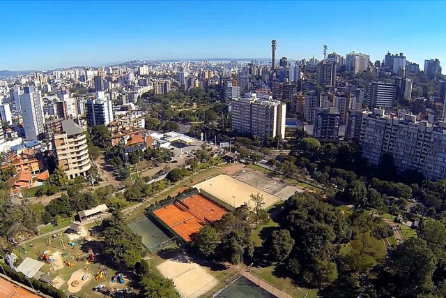Fachada de arquitetura moderna do Grêmio Náutico União visto de baixo, destacando as varandas geométricas brancas e marrons sob o céu do pôr do sol em Porto Alegre.